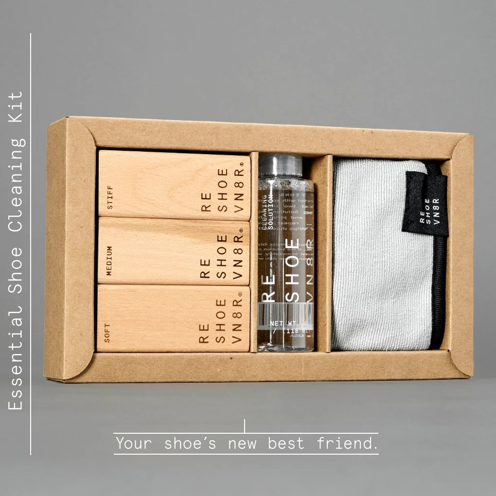 A box of Reshoevn8r gold nike high basketball shoes with cutouts boots resting on a white background. The kit includes a bottle of cleaning solution, three brushes in different softness levels (soft, medium, and stiff), and a microfiber towel. Text on the box indicates the brushes are for use on suede, leather, mesh, canvas, nubuck, plastic and rubber shoes.